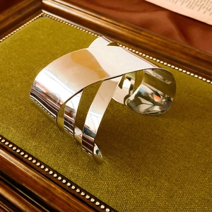 Detailed view of silver geometric wide cuff bracelet on a luxury texture display