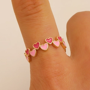 Dettaglio dell'anello a forma di cuore in smalto rosa placcato oro sul dito
