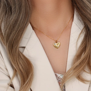 Close-up of golden heart pendant necklace with transparent gemstone on neck