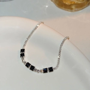 Macro detail of silver chain bracelet with clear zircons and black rectangular stones