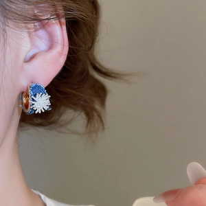 Detailed view of a C-shaped earring with blue denim fabric and a silver starburst charm