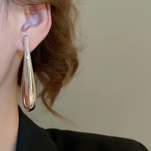 Close-up of model wearing silver long teardrop earrings with a polished metallic finish