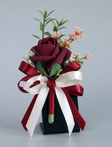 Gros plan de la boutonnière de mariage en rose artificielle rouge foncé avec rubans de satin
