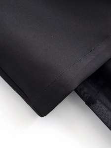 Dettaglio macro delle cuciture tra tessuto nero e materiale mesh sul vestito a fascia