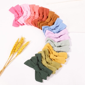 Colorful linen bow clips arranged in a vibrant gradient arch on a clean white background