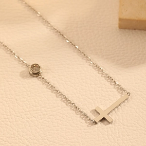 Détail d'un collier en acier inoxydable argenté avec pendentif diamant rond et croix