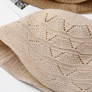 Close-up detail of a beige knitted bucket hat featuring intricate hollow-out lace patterns