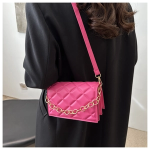Close-up of quilted fuchsia handbag with thick gold chain and adjustable shoulder strap