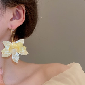 Détail de la boucle d'oreille en forme de C en résine jaune pâle au fini perlé