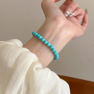 Detail of a sky blue turquoise beaded elastic bracelet worn on a female wrist