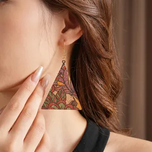Vintage bohemian geometric leather print triangle earrings worn by model on brown background