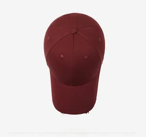 Detail of burgundy cotton baseball cap featuring white circular slogan embroidery and distressed brim