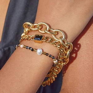 Layered 18k gold plated bracelet set with black gem and pearls on a model's wrist