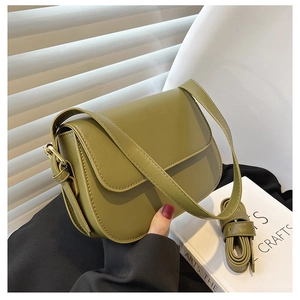 Close-up of olive green vintage saddle bag with smooth texture and adjustable strap