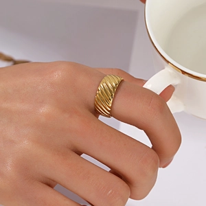 Golden croissant-style dome ring with ribbed texture worn by a model in a minimal setting