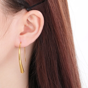 Close-up of golden teardrop earring on model showing smooth curved minimalist design