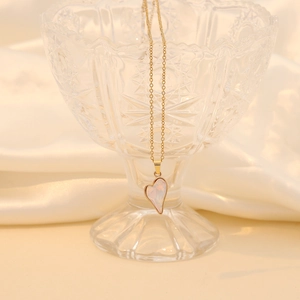Macro view of gold asymmetric heart pendant necklace with pearlescent inlay on silk