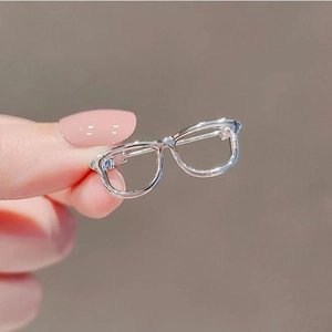 Close-up of miniature transparent resin glasses held by fingers showing tiny detail size