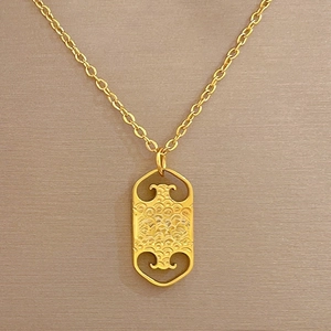 Golden titanium steel necklace with rectangular auspicious pendant on beige fabric