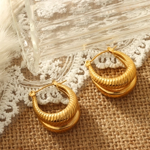 U-shaped gold-plated stainless steel earrings with textured spiral design on lace background