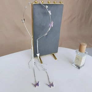Close-up of silver metal headband featuring purple crystal butterflies and long tassels