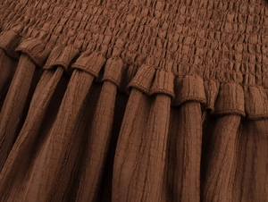 Detailed close-up of brown smocked fabric with delicate vertical pleated texture