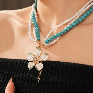 Gros plan d'un collier multicouche en perles de turquoise avec pendentif fleur et strass