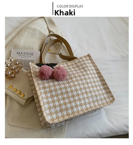 Detail of khaki houndstooth tote bag with pink cherry pompom on stylish white bedding
