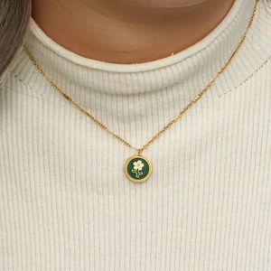 Close-up of a model wearing a green enamel flower pendant necklace with 18K gold plating