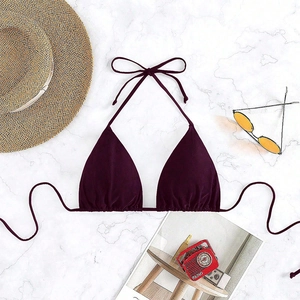 Deep purple lace-up bikini top flat lay with sun hat and glasses on marble surface