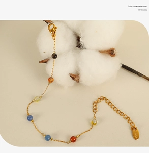 Detail showing gold chain with colorful beads, lobster clasp and S.steel logo tag