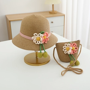 Detail of a girl's straw sun hat and matching bag with woven flowers and polka dot ribbon