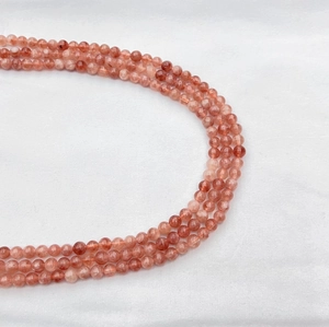 Natural orange sunstone round loose beads for DIY jewelry making on white fabric