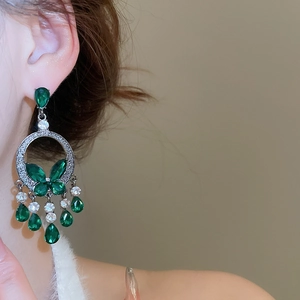 Detail view of emerald green butterfly tassel earrings with silver rhinestones on model