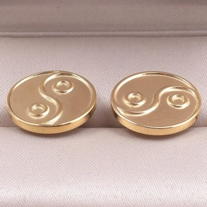 Macro view of gold-tone heart-shaped 304 stainless steel earrings with Tai Chi relief design