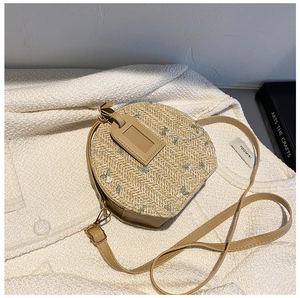 Detail of pink flower embroidery on a straw round crossbody bag with PU strap