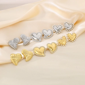 Detail of 18K gold and silver heart earrings with pearls on champagne silk fabric