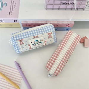 Detail of plaid pencil pouches with happy labels and zipper closure for students