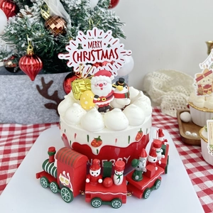 Close-up of Merry Christmas acrylic cake topper with festive snowman and Santa dolls