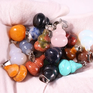 Close-up of colorful gourd-shaped natural gemstone pendants held on a white gloved hand