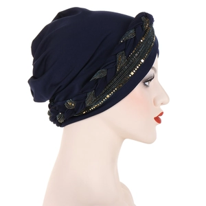 Detail of dark blue turban hat featuring a gold and black braided sequin band for women