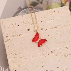 Détail macro du pendentif papillon rouge avec chaîne dorée et zircons incrustés