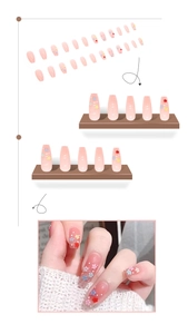 Gros plan sur des ongles press-on dégradés roses avec fleurs 3D colorées et cristaux