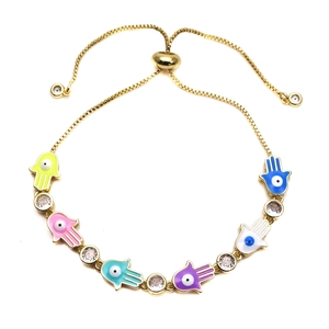 Detail of adjustable gold Hamsa Hand bracelet with colorful enamel Evil Eye charms and zircons