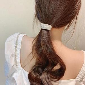 Elegant woman wearing a sparkling rhinestone hair ring on brown wavy hair with white blouse