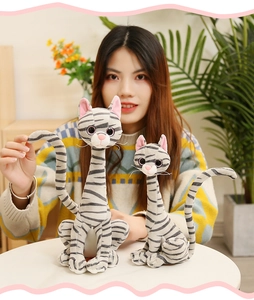 Detailed view of two soft grey striped plush cats held by a model in a cozy home setting