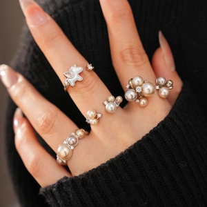 Close-up of elegant silver rings with pearls and zircon on hand against a black sweater
