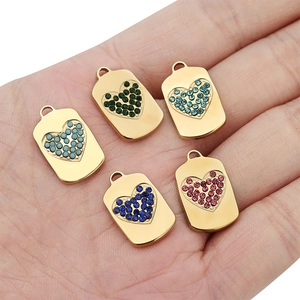Macro shot of rectangular gold pendants with colorful heart-shaped rhinestones on a palm