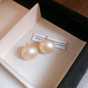 Macro shot of large round champagne pearl studs in a black velvet jewelry box tray