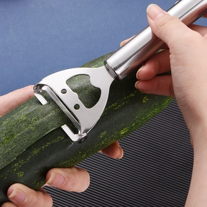 Dual-purpose stainless steel peeler and bottle opener being used on a cucumber